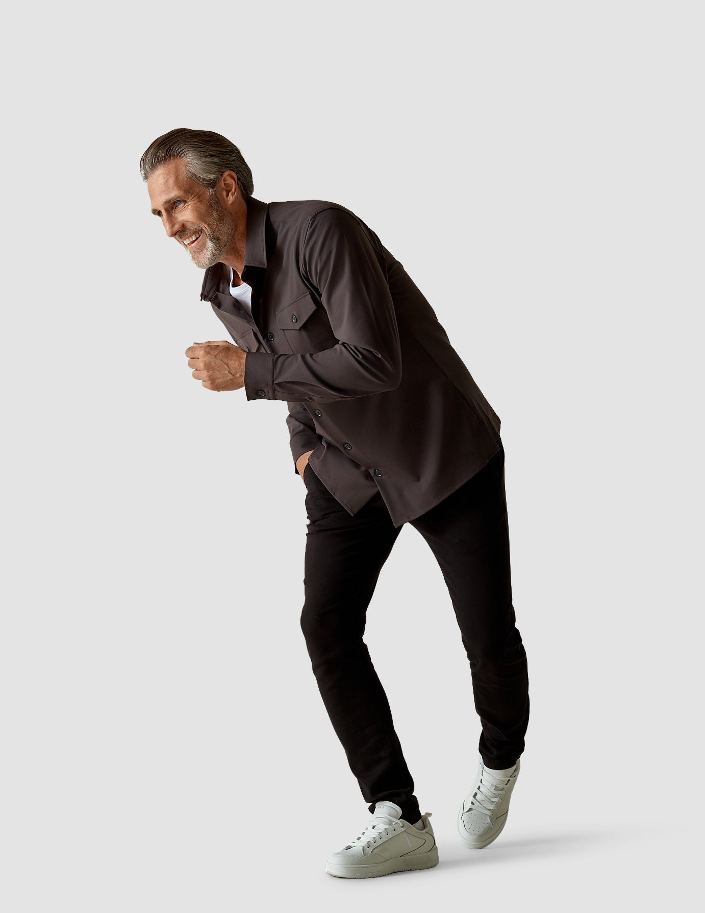 Model in full body wearing a dark shadow/Grey overshirt with a white t-shirt underneath